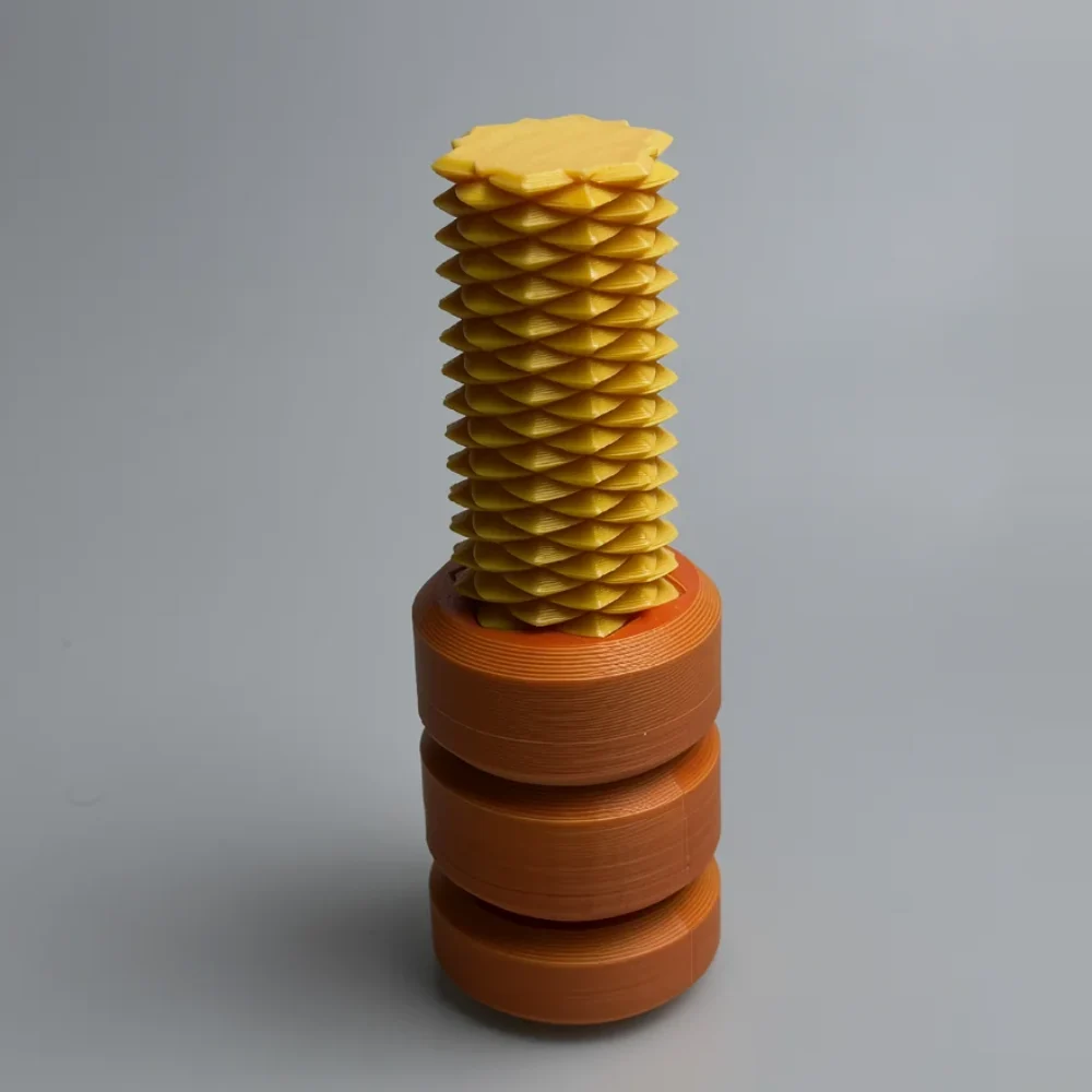 Two Way Screw: yellow and orange 3D printed helical mechanical structure, helical column of diamond-shaped facets
