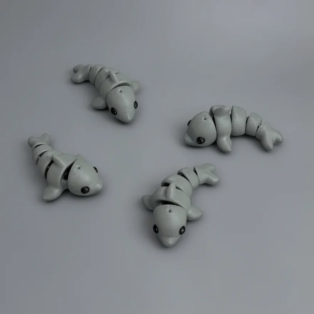 Baby Dolphin: light grey and black (eyes) articulated fish figure, blocky segmented body