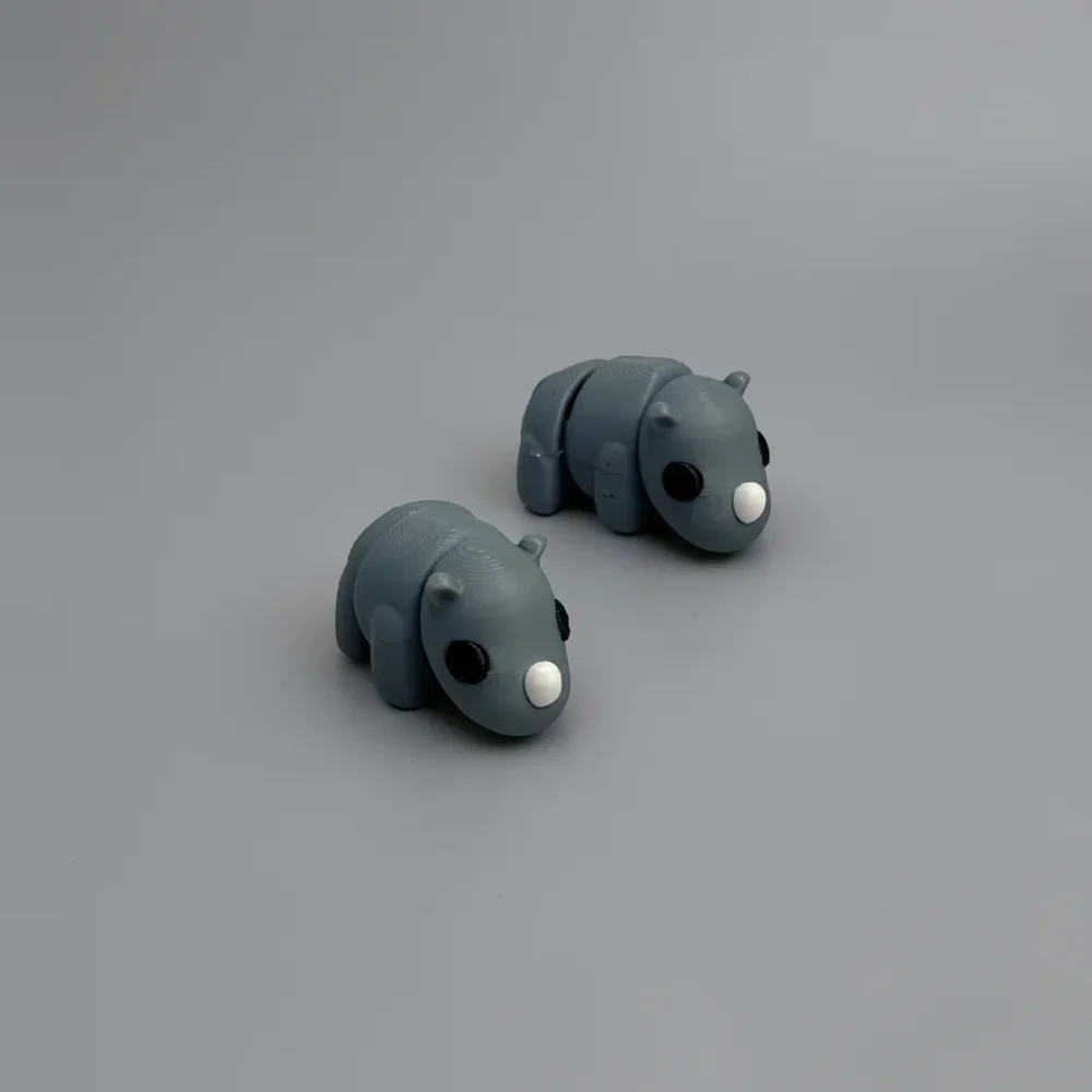 Baby Rhino: slate-grey and black pair of stylized rhinoceros figurines, large solid black circular eyes