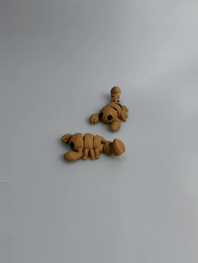 Baby Scorpion: tan and black Two scorpion-like insect figurines, each a single continuous articulated/segmented piece