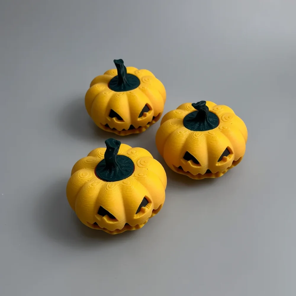 Pumpkin Spinner: yellow-orange and dark teal three small Jack-o'-lantern pumpkin figurines
