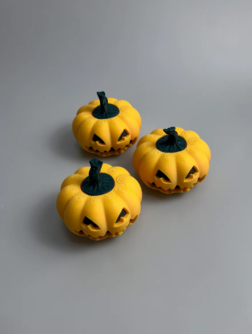 Pumpkin Spinner: yellow-orange and dark teal three small Jack-o'-lantern pumpkin figurines