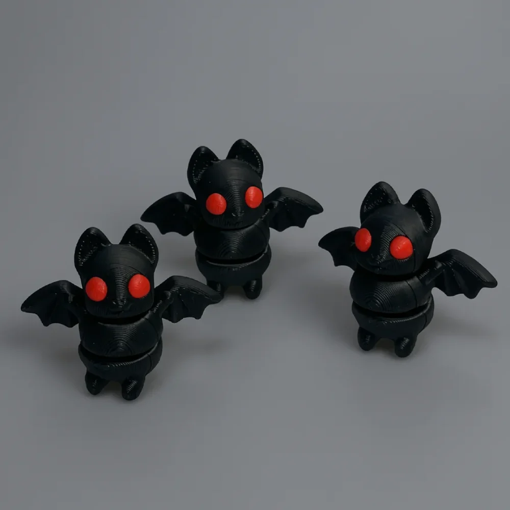 Tiny Bat: black and red three bat figurines, each with a segmented body joined at a horizontal midline