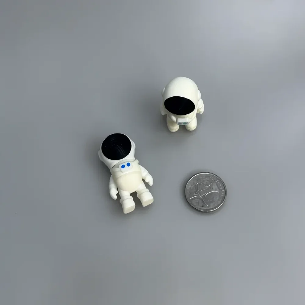 Tiny Astronaut: white and black two miniature astronaut figurines (separate pieces), black circular helmet visors