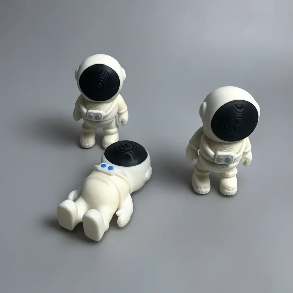 Tiny Astronaut: off-white and black three astronaut/spaceman figurines, large spherical helmet with black visor