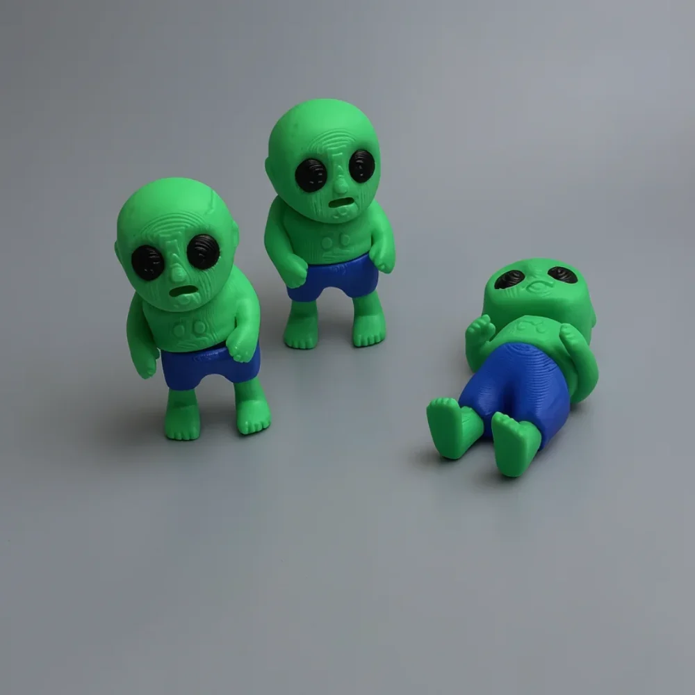Tiny Zombie: green and blue cartoonish green alien toy figure (three figures shown in three different poses)