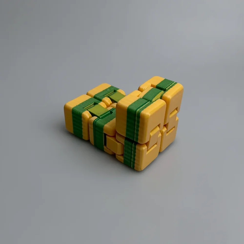 Infinity Cube: golden-yellow and dark green interlocking cube puzzle, L/V-shaped two-arm cluster joined at a corner